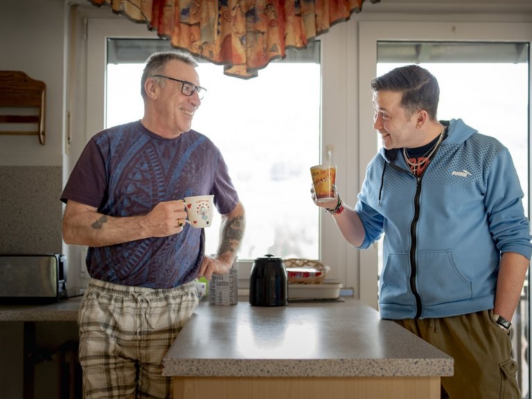 Zwei Maenner trinken in der Kueche einen Kaffee 